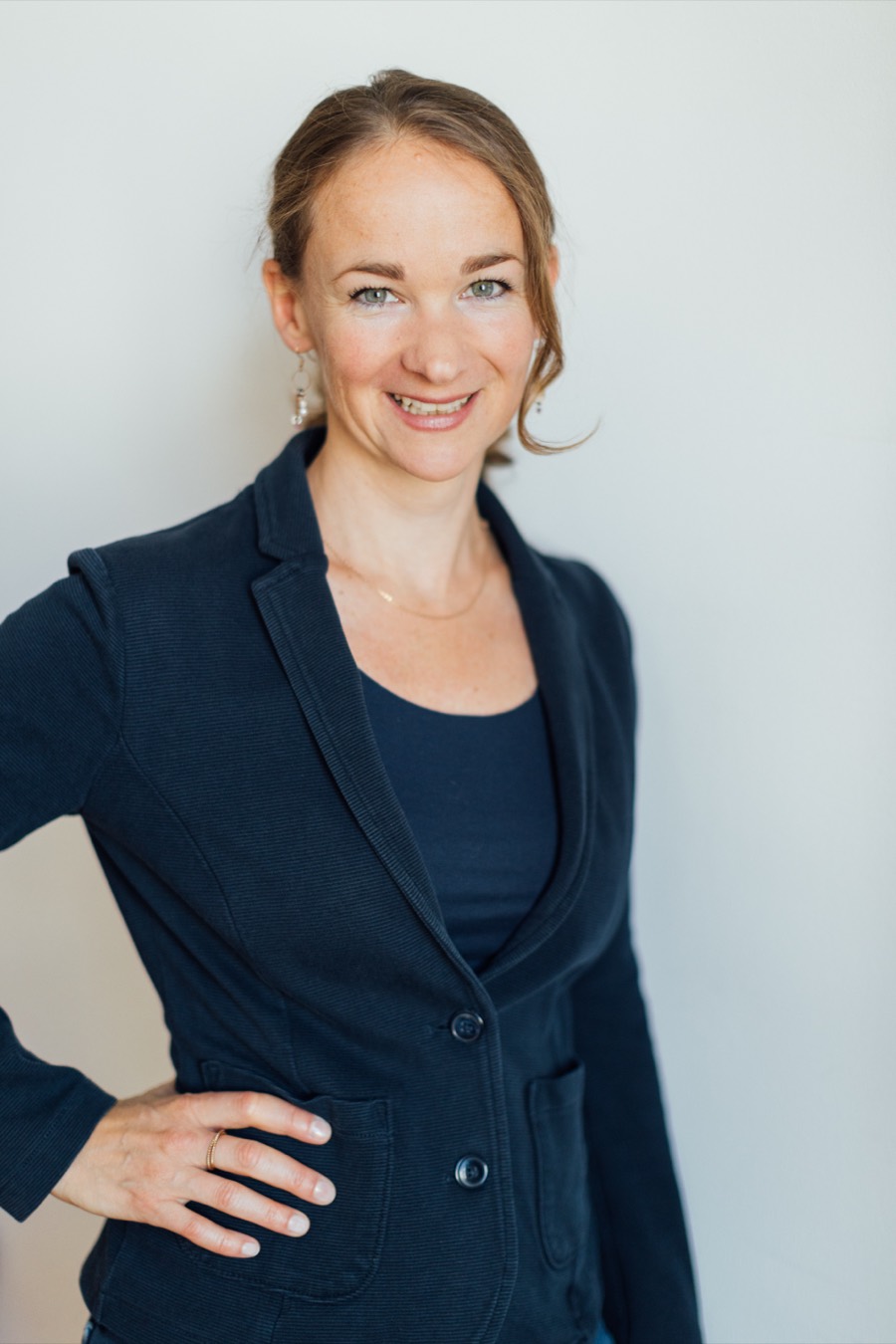 Portr&auml;t von Katharina Pichler im dunkelblauen Blazer vor heller Wand